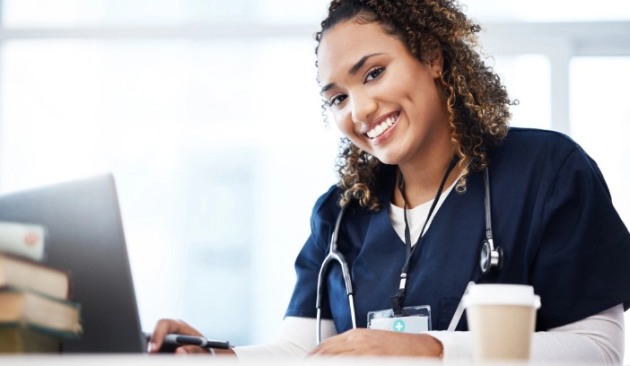 Eine Pflegefachkraft im blausitzt an einem Laptop und schaut sich Gukp Jobs bei Flexiholding an.